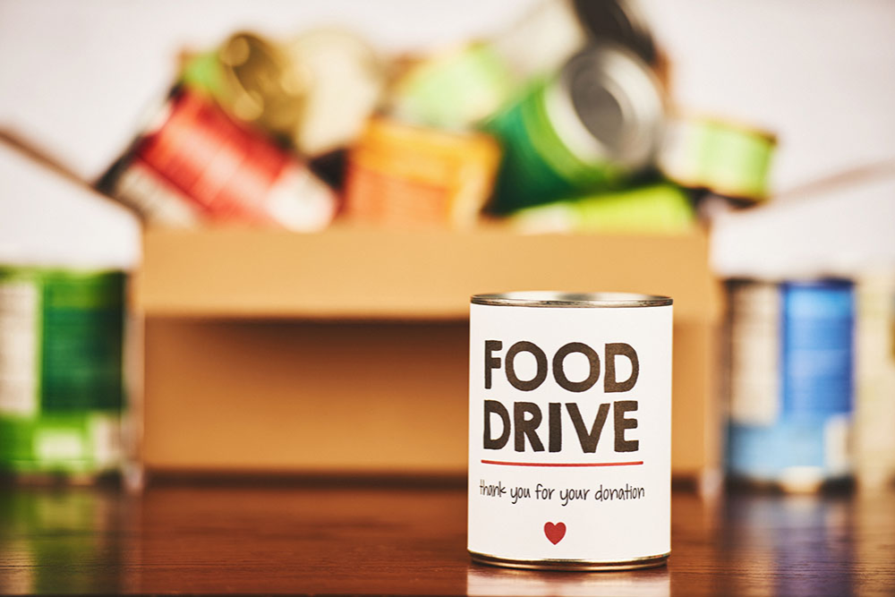 Can good donations in a box with a can labeled "Food Drive, Thank you for your donation"