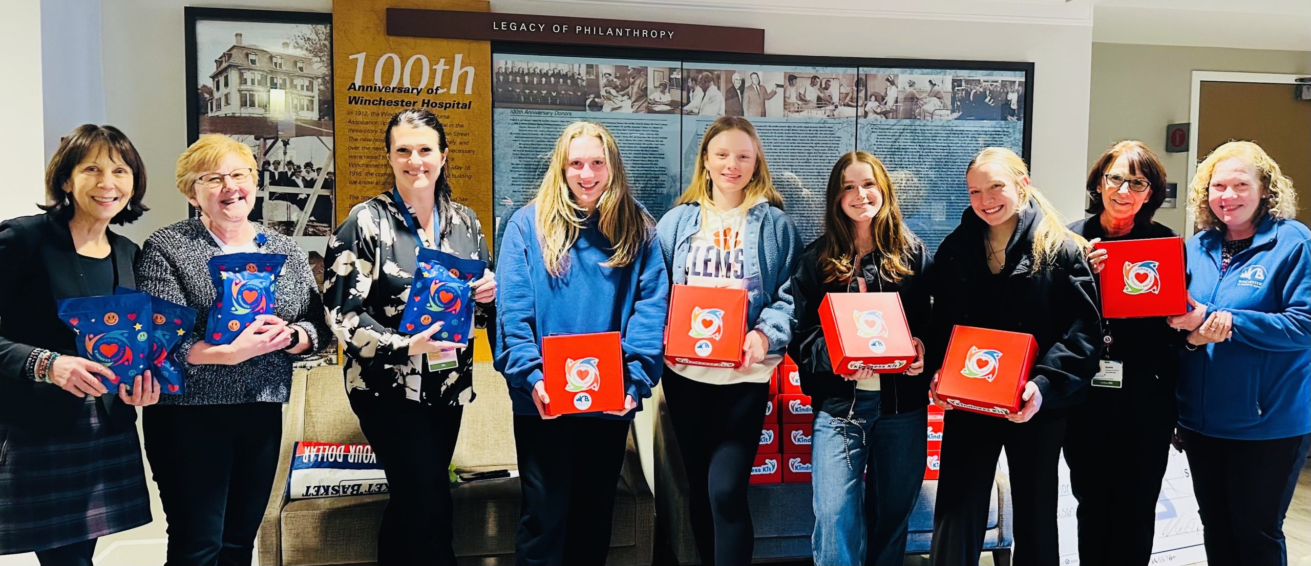 group of women from the Hospital with Girls basketball team hold red Connor Kindness kits